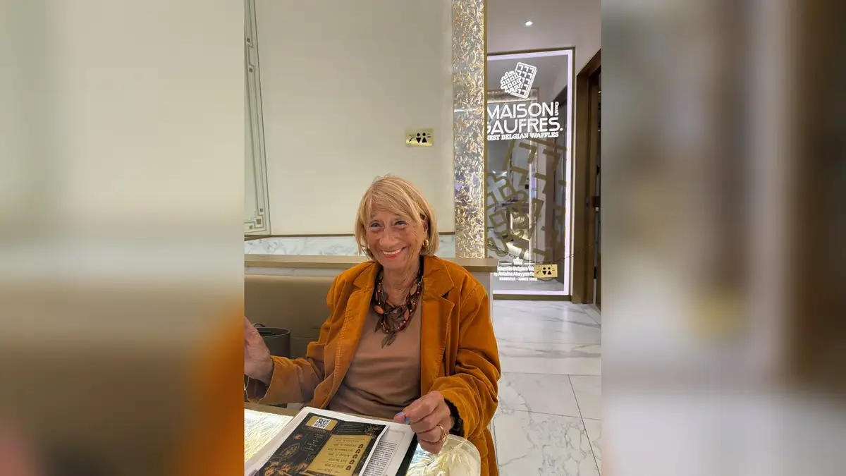Sonia Neefs sonríe con una chaqueta ocre, sentada en La Maison des Gaufres de Bruselas
