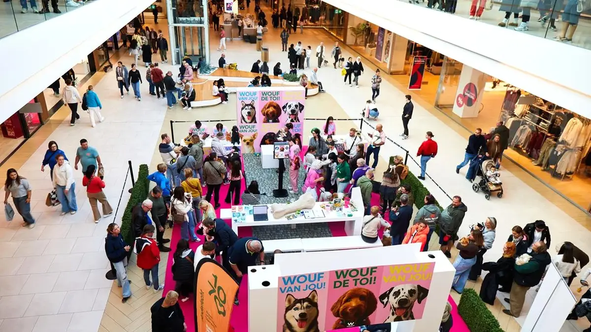 البهو المركزي لـWestland Shopping في أندرلخت خلال Dog Day، مع سجادة وردية وأكشاك وزوار برفقة كلابهم.