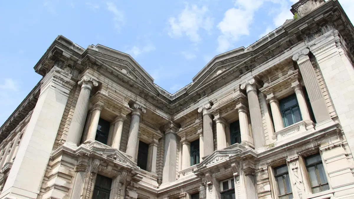 La façade du Palais de Justice de Bruxelles, détail des colonnes et frontons sous un ciel bleu