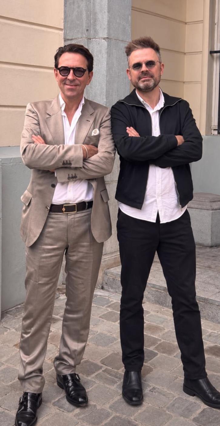 Photo en pied : Carl De Moncharline et Sébastien Boussois devant une façade claire, bras croisés